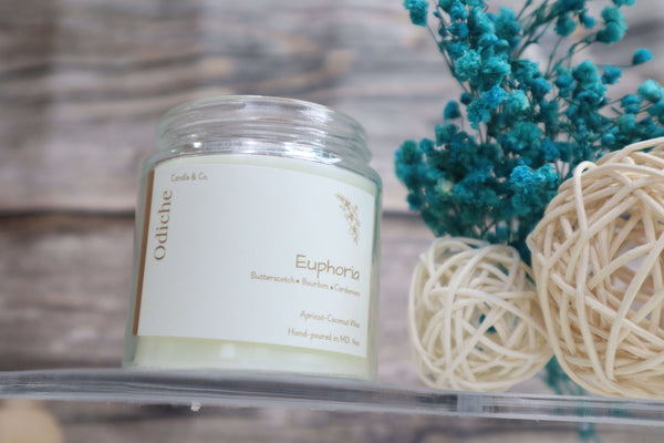 Euphoria hand-poured soy candle in a clear jar, featuring warm buttery scents and eco-friendly design.