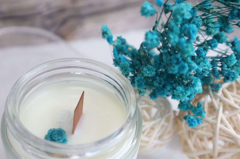Hand-poured soy candle with teal flowers, showcasing luxury scented candles in eco-friendly glass.