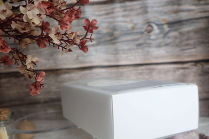 Elegant white box with floral decor against a rustic wooden background, perfect for gift presentation.